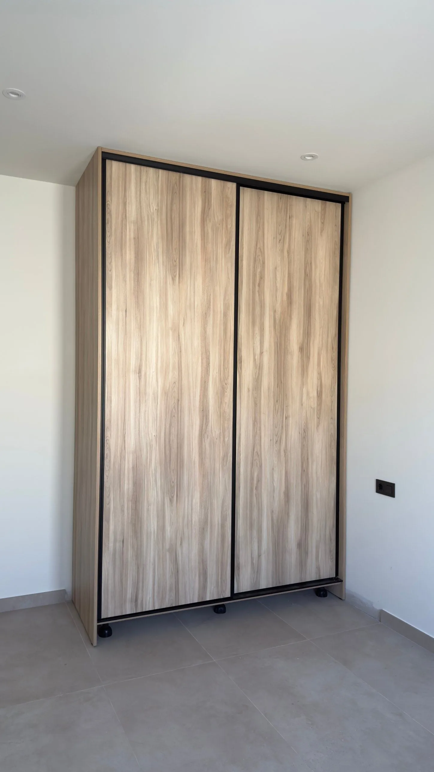 Armario a medida con dos puertas correderas en acabado madera y perfiles negros