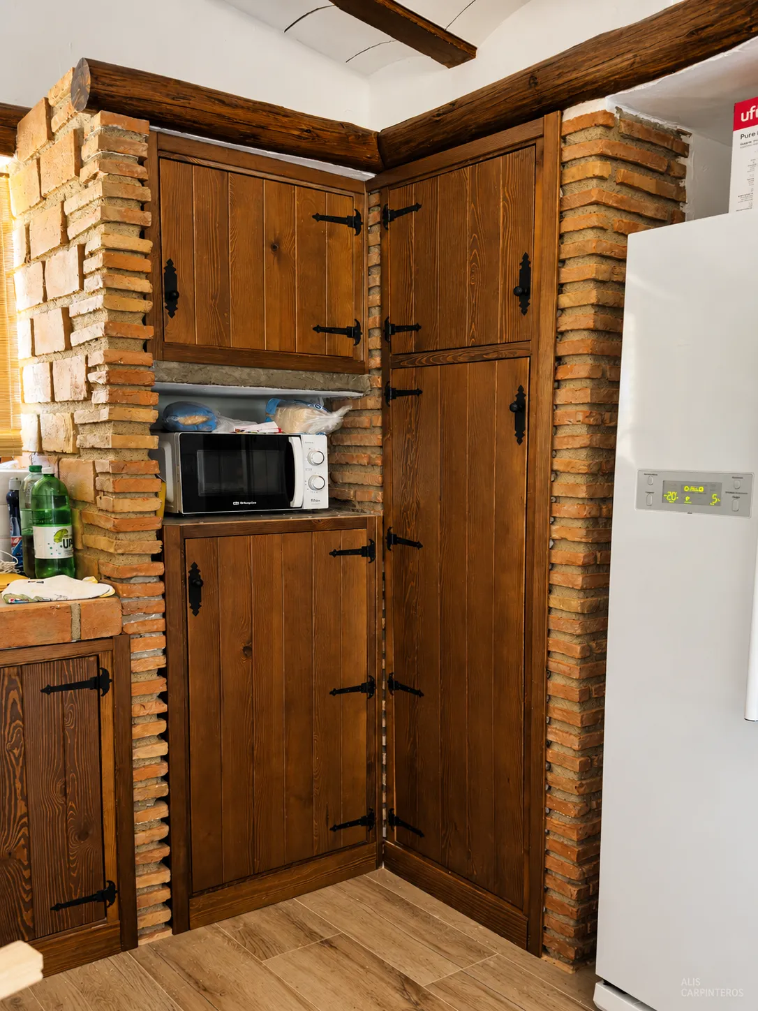 Alacena y columna de madera rústica con bisagras de forja entre pilares de ladrillo
