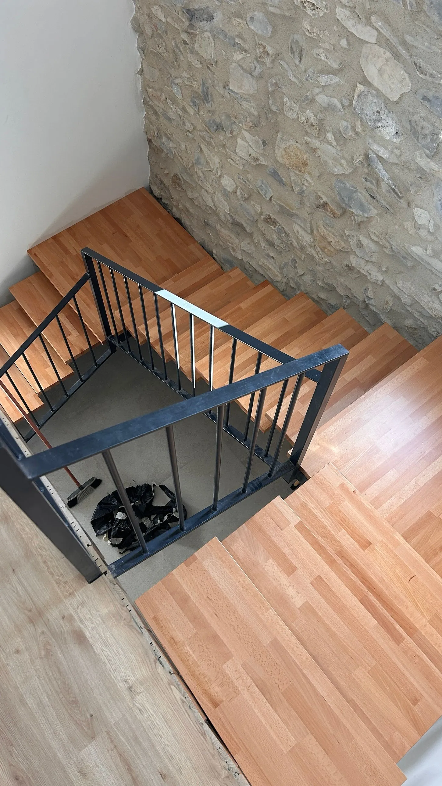 Escalera de madera con barandilla metálica vista desde la planta superior