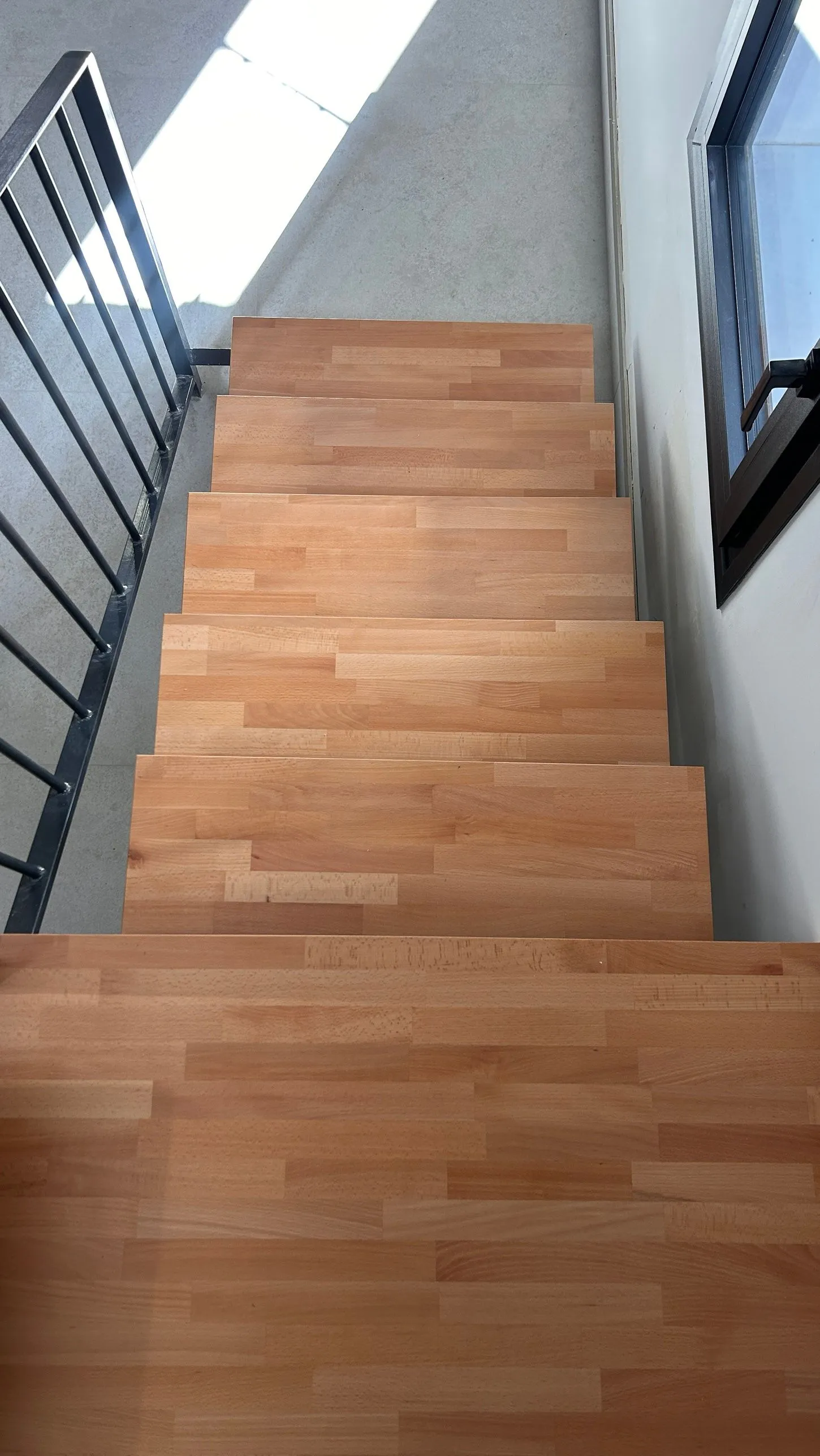 Tramo de escalera con peldaños de madera y barandilla de barrotes