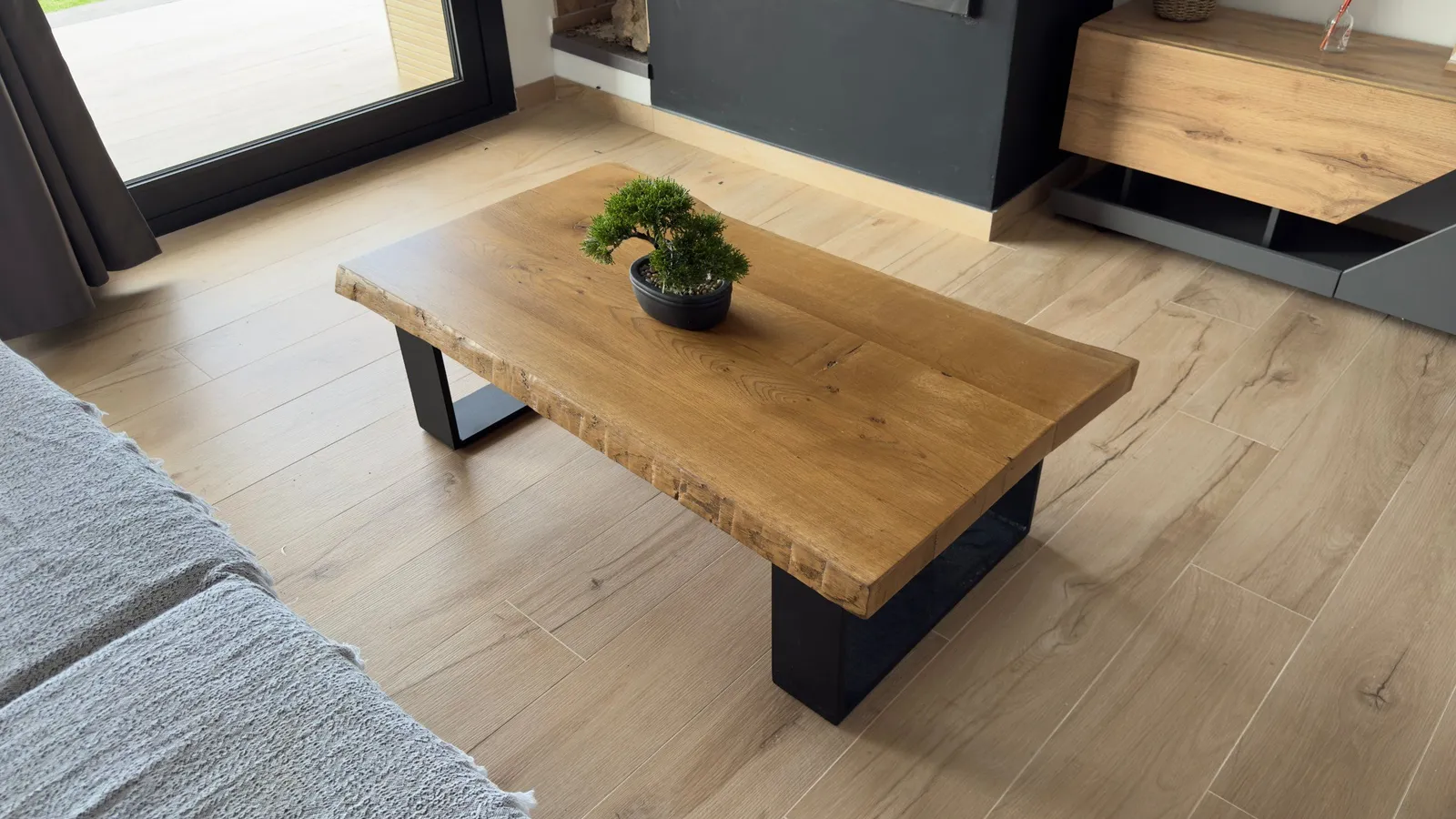 Mesa de centro de madera maciza con canto natural y patas de acero negro en un salón
