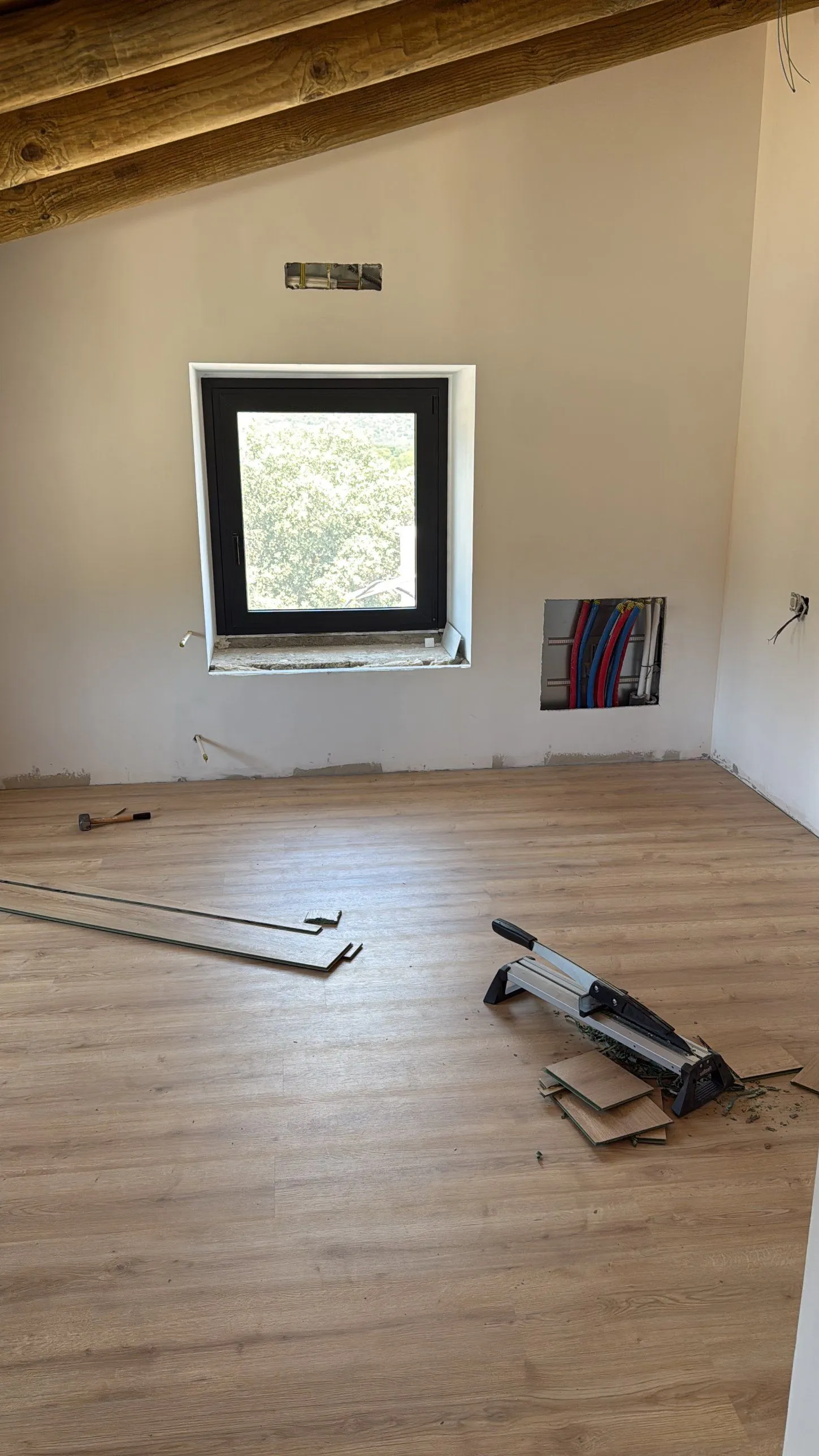 Suelo de lamas en tono roble recién colocado en una habitación abuhardillada con vigas de madera