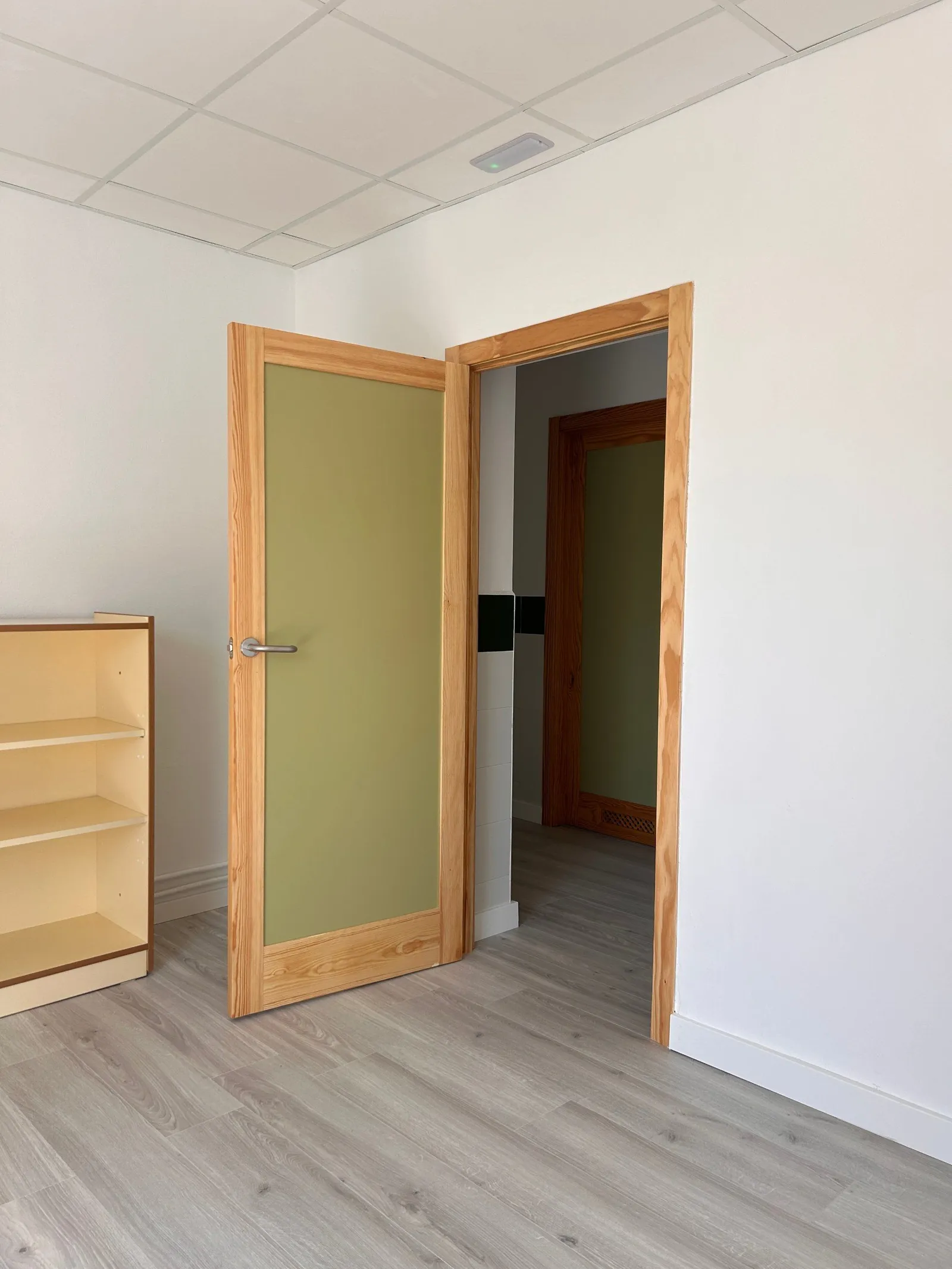 Puerta de pino con panel verde sobre suelo de lamas gris claro